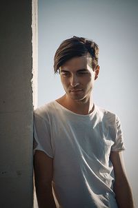 Young man standing by wall