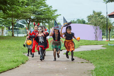 Girls in costumes running on footpath during halloween