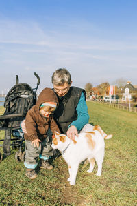 Grandfather and granddaughter with cat on grass