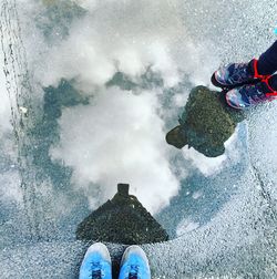 Low section of friends standing in front of puddle with reflection at street