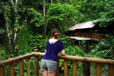 Rear view of man standing by railing in forest