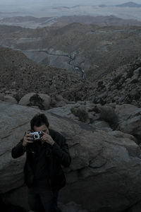 Full length of man photographing on rock