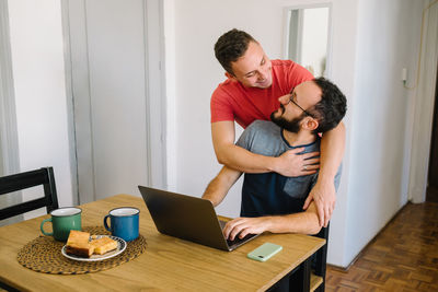 Two men looking at each other with a laptop.