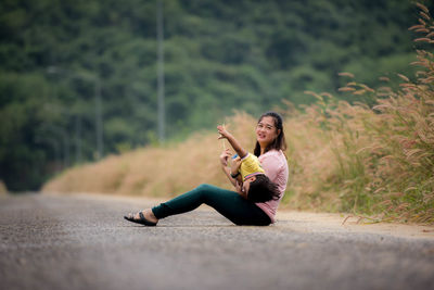 Full length of woman sitting with son on road