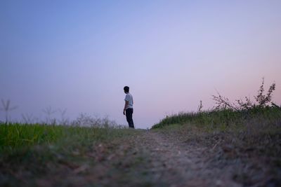 Man standing on field against clear sky during sunset