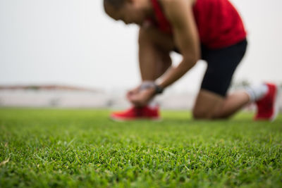 Man tying shoelace on playing field