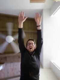 Cheerful man with arms raised at home