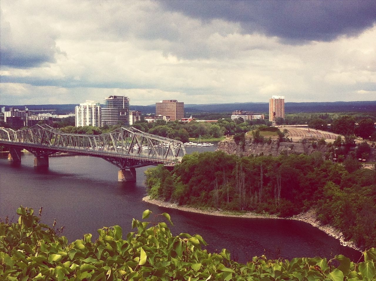 architecture, built structure, sky, cloud - sky, bridge - man made structure, connection, water, cloudy, river, tree, building exterior, cloud, bridge, transportation, nature, engineering, day, overcast, plant, outdoors