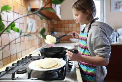 Midsection of woman standing in kitchen at home