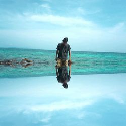 Rear view of man on sea against sky