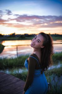 Side view of young woman looking away against sky during sunset