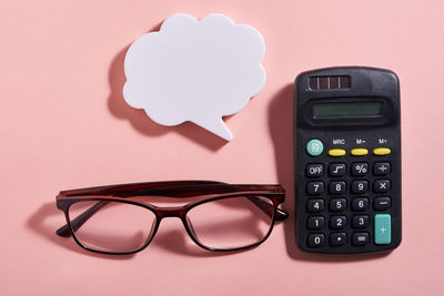 High angle view of calculator against pink background