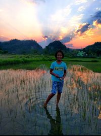 Full length portrait of happy girl standing on field against sky