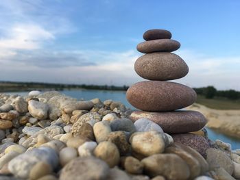 Close-up of stacked stones at beach against sky