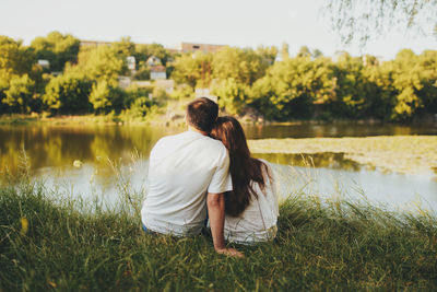 Rear view of couple standing on lake against plants