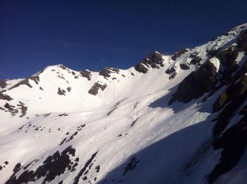 Scenic view of snowcapped mountains against clear blue sky