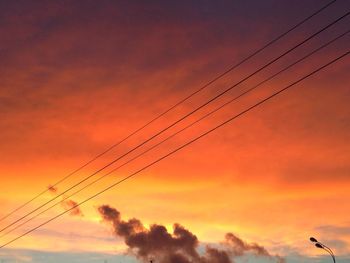 Low angle view of electricity pylon against cloudy sky