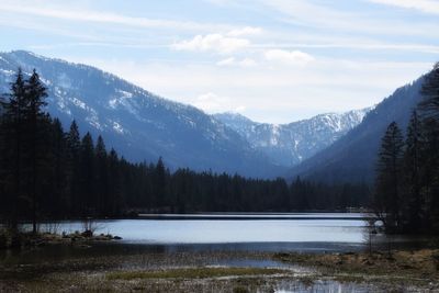 Scenic view of lake by snowcapped mountains against sky