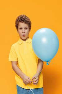 Portrait of boy with balloons against yellow background
