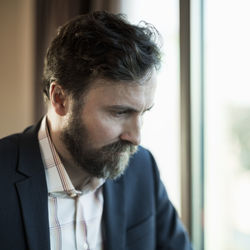 Businessman looking down by window in hotel room