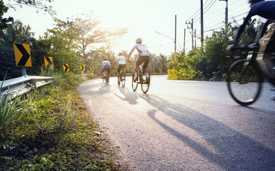 Rear view of people riding bicycle on road