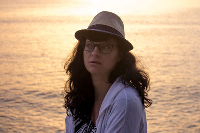 Portrait of beautiful young woman in sea during sunset