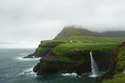 Scenic view of sea and cliff against sky