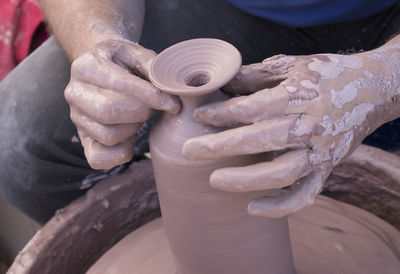 Midsection of man molding shape on pottery wheel