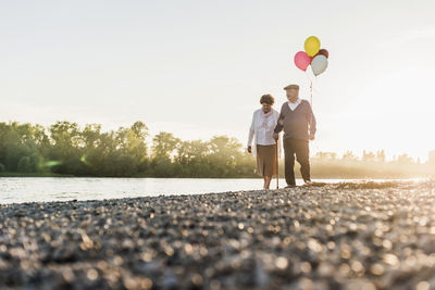 Senior couple with balloons strolling at riverside