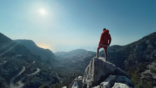 Rear view of man standing on rock against sky