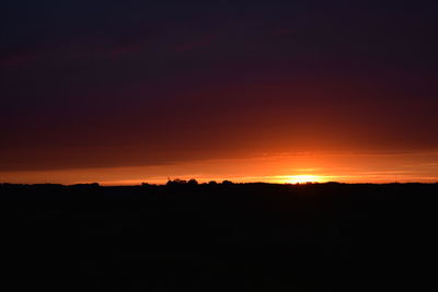 Silhouette landscape against dramatic sky during sunset