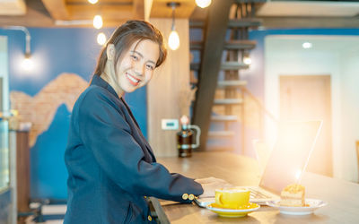 Young woman smiling while sitting on table