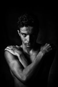 Close-up portrait of shirtless man against black background