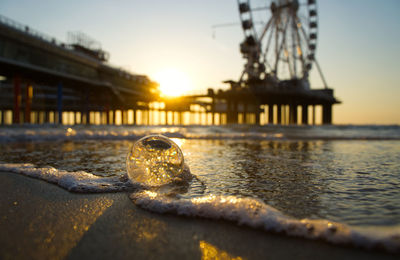 Close-up of water at beach against sky during sunset