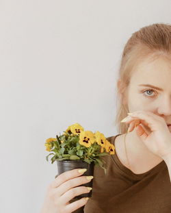 Portrait of woman holding flower against white background