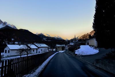 Road by frozen mountain against clear sky during winter