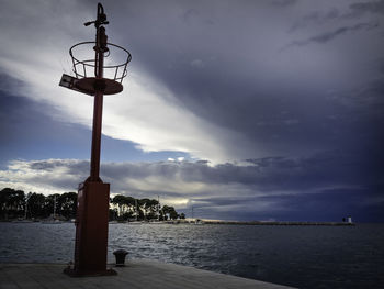 Street light by sea against sky at dusk