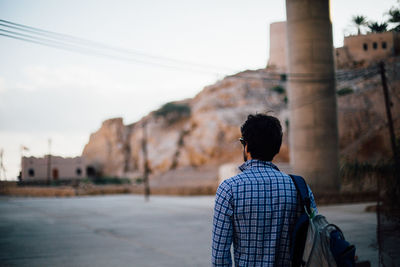 Rear view of woman standing by wall