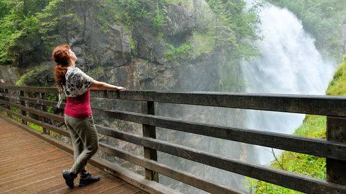 Side view of woman looking at waterfall