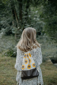 Rear view of woman standing against trees