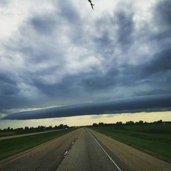 Country road against cloudy sky