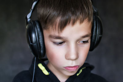 Close-up of thoughtful boy listening music in headphones