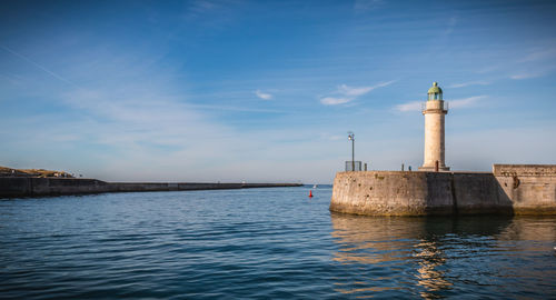 Lighthouse by sea against sky