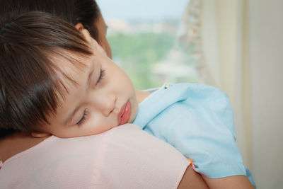 Close-up of mother carrying sleeping boy at home