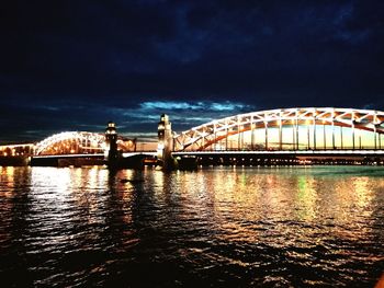 Bridge over river against sky in city at night