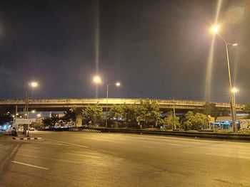 Illuminated street against sky at night