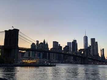 Bridge over river in city against clear sky