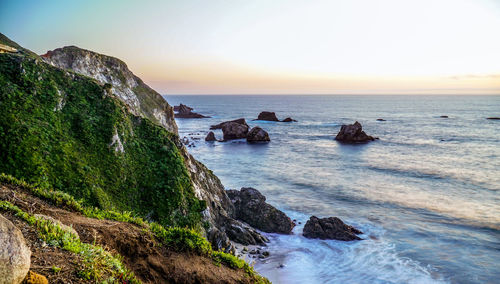 Scenic view of rocks in sea against clear sky