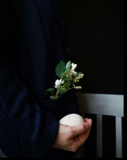 Midsection of woman holding flowers and egg