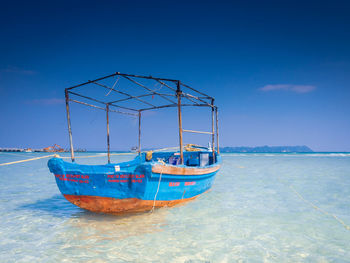 Fishing boats moored on sea against blue sky